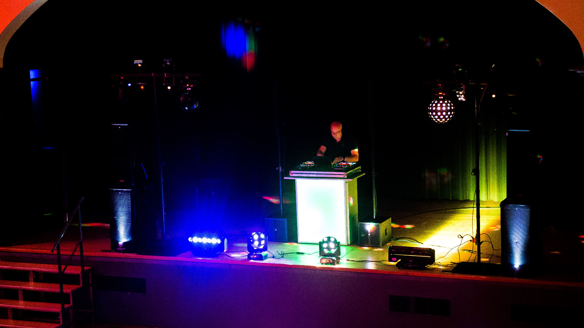 DJ der Bischof auf der Bühne mit farbigem Bühnenlicht und Discokugel